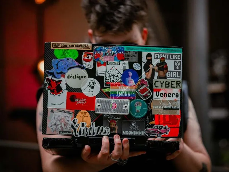 Laptop covered in custom printed stickers, held up by its owner